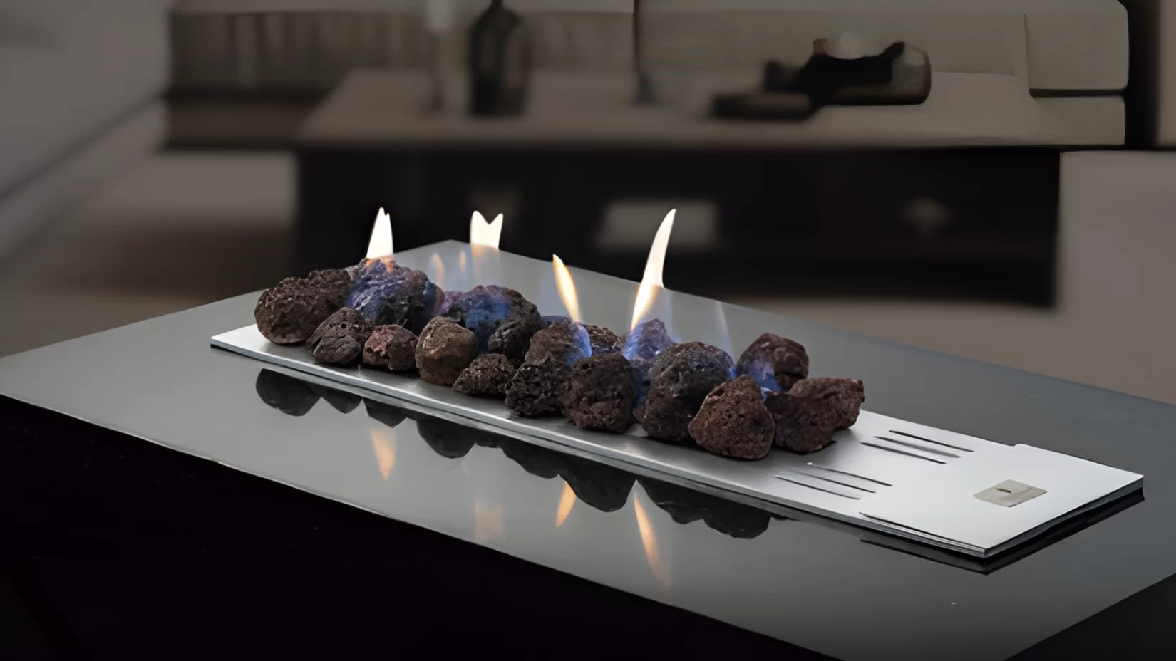 Lareira ao centro da sala, com mesa e sofá cinza ao fundo, projeto da melhor empresa de lareira do Brasil: Fogo&Art.